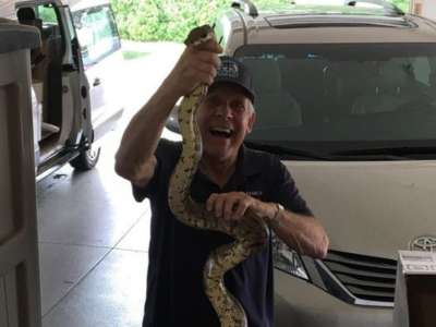 Certified wildlife removal expert holding a boa constrictor snake after removing it from a customer's apartment.