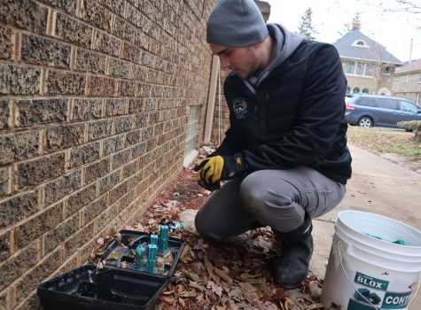 Certified pest control technician refilling a rodent bait station as part of a continuous rodent maintenance program.